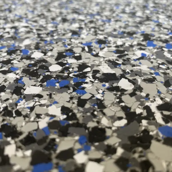 Close-up of a textured surface with a mix of blue, black, white, and gray scattered flakes, resembling a speckled pattern.