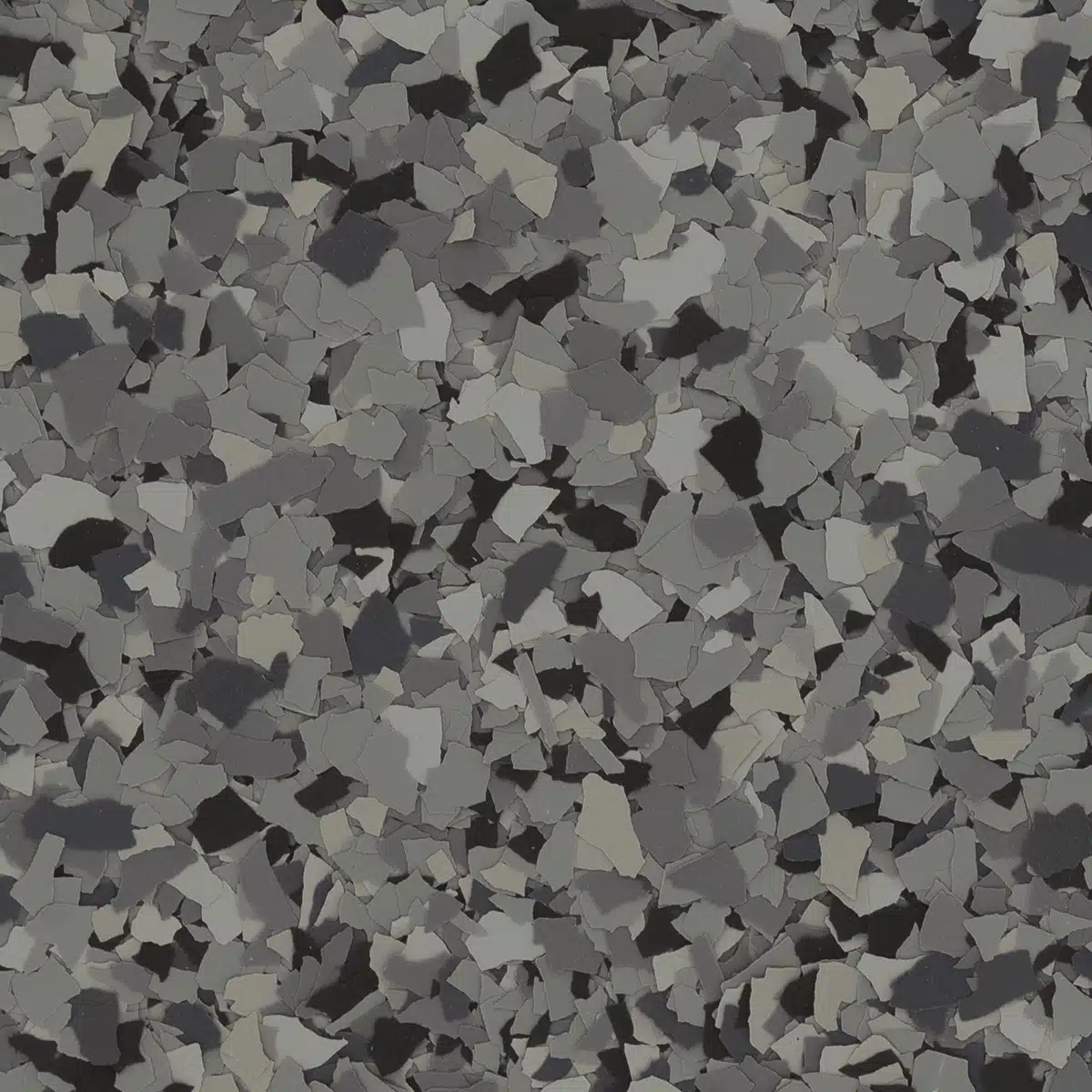 A close-up of a textured surface, featuring an abstract pattern of black, gray, and white flakes on a flat, dark background.
